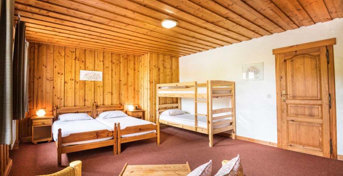 Four beds in a hotel room with wooden furniture