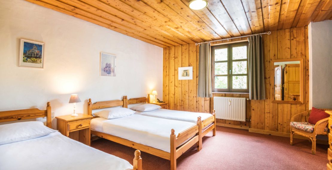 Three beds in a room with wooden furniture