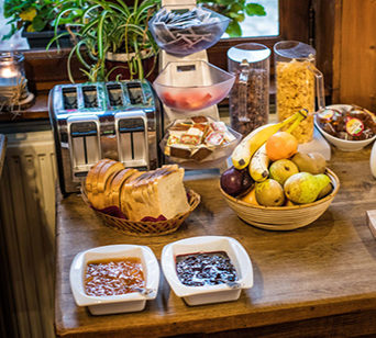Breakfast buffet with jams, breads, fruits, and cereals